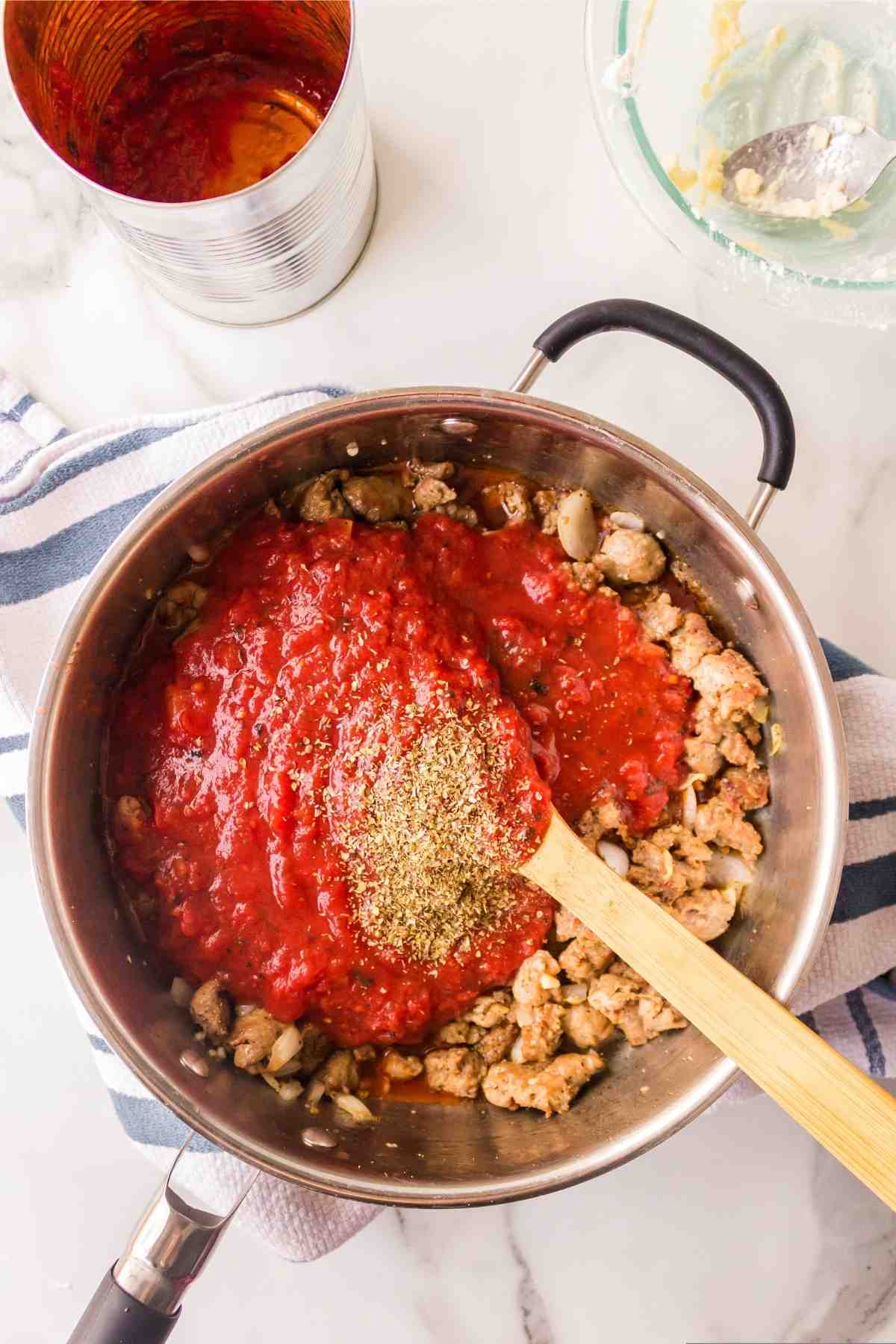 Tomato sauce and seasonings on top of browned Italian sausage. 