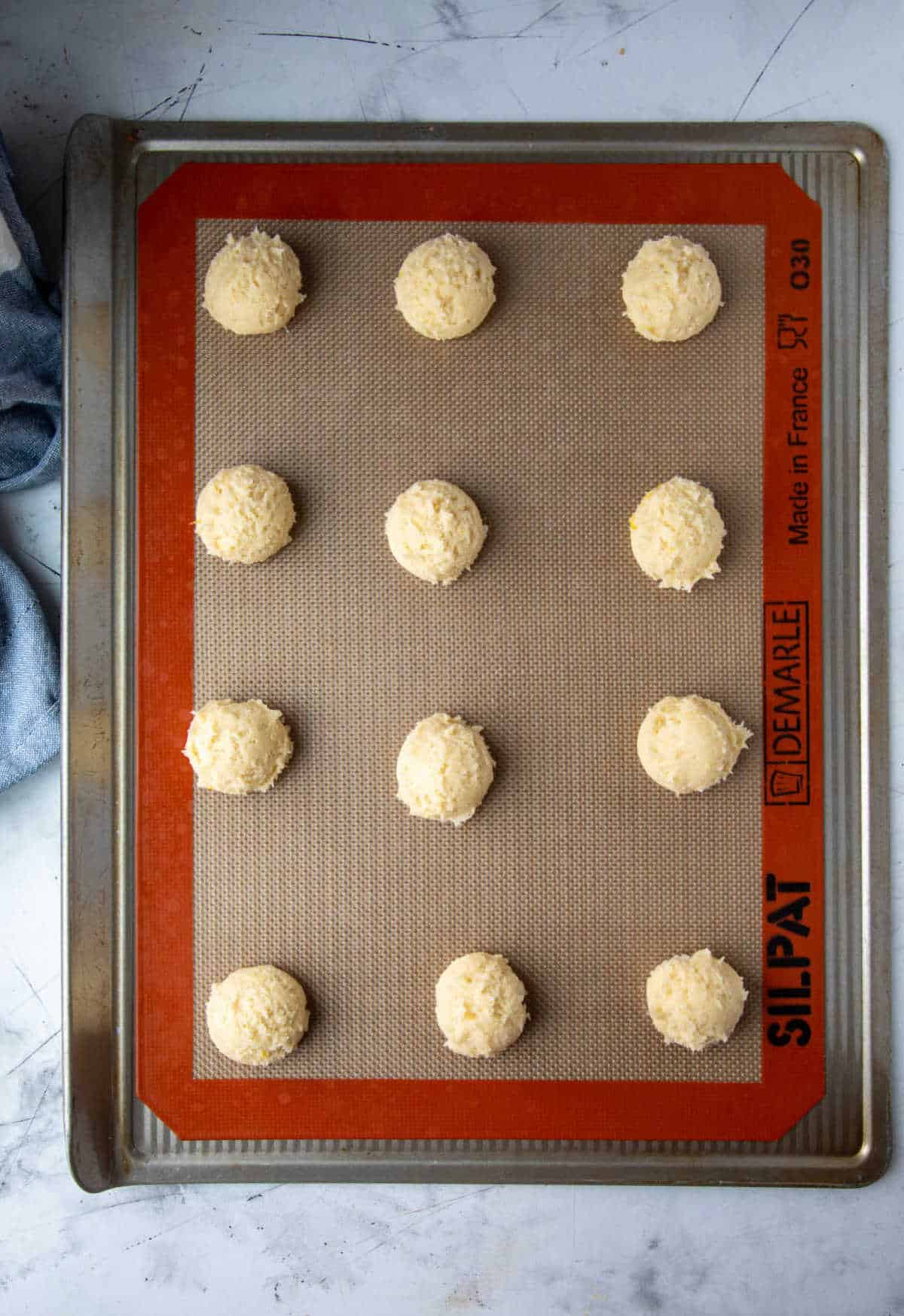 Lemon cookie dough scoops on a baking sheet.