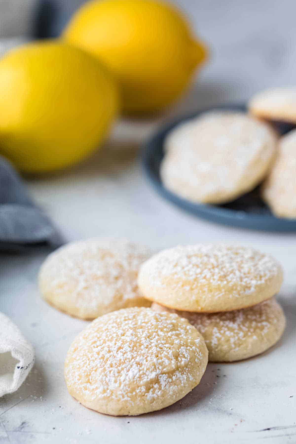 Stack of lemon cookies next to a blue plate with cookies.