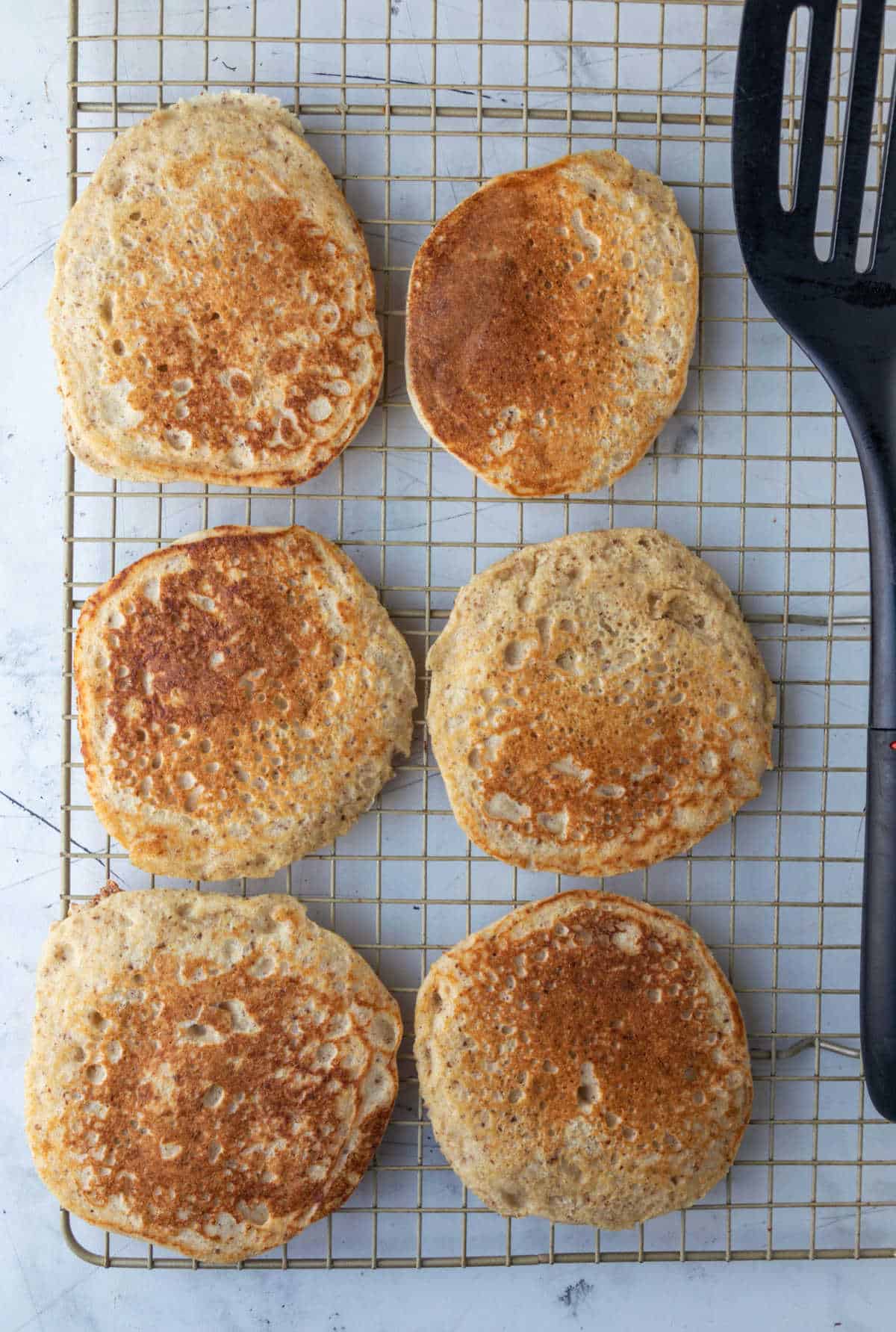 Whole wheat pancakes cooling on a wire rack. 