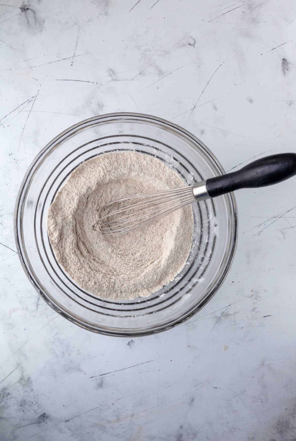 Dry ingredients for whole wheat pancakes in a glass mixing bowl. 