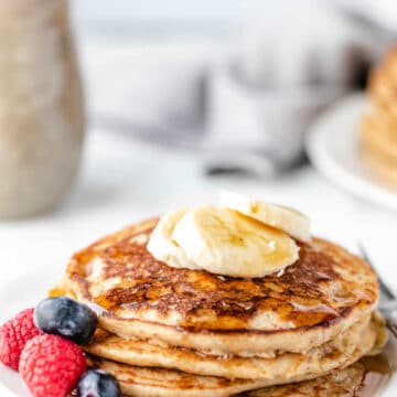 Stack of whole wheat pancakes topped with banana slices.