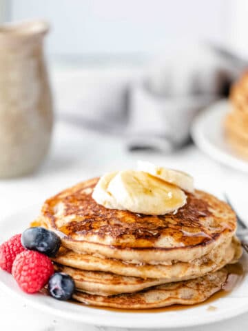 Stack of whole wheat pancakes topped with banana slices.