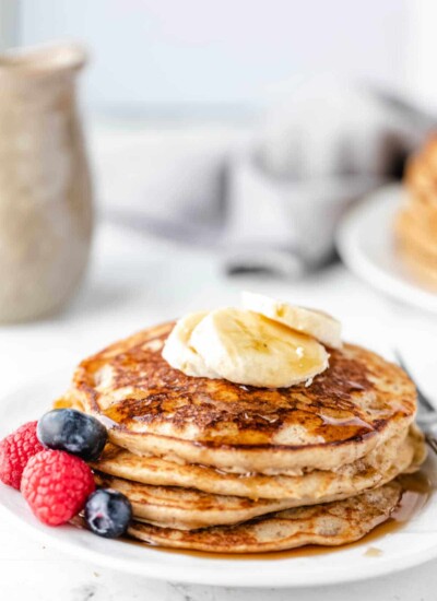 Stack of whole wheat pancakes topped with banana slices.