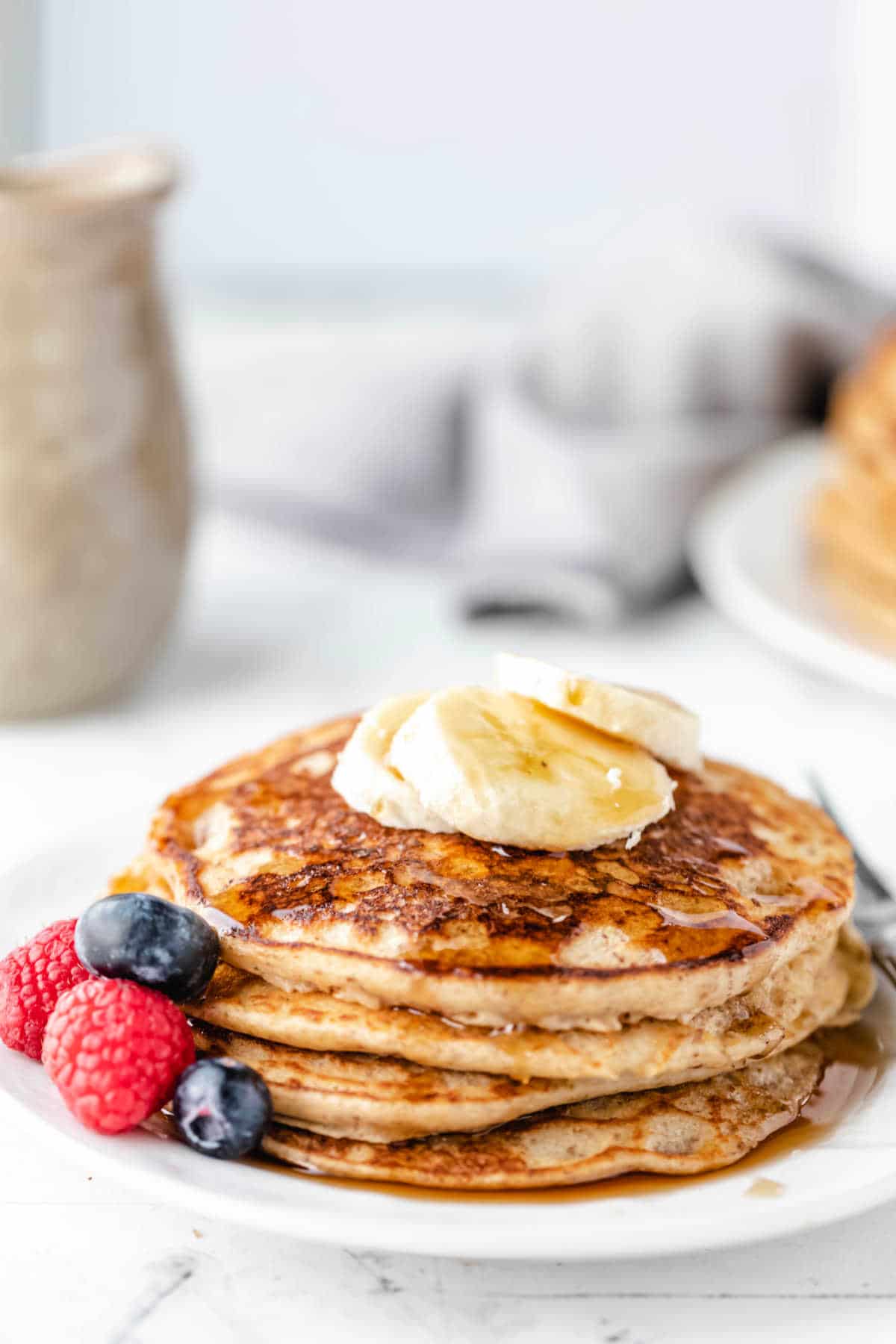 Stack of whole wheat pancakes topped with banana slices.