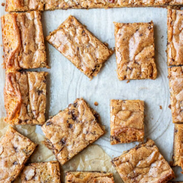 Partially cut tray of blondies on parchment paper.