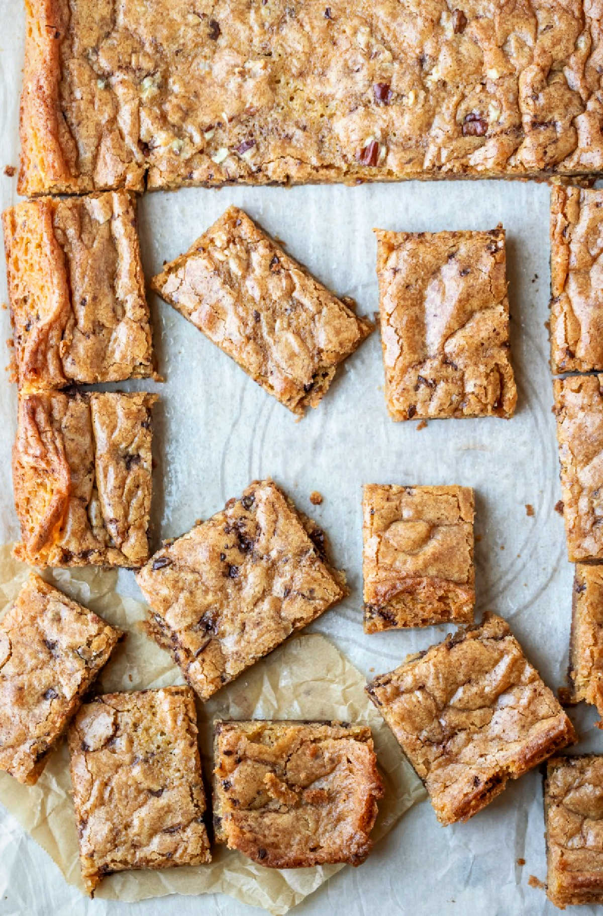 Partially cut tray of blondies on parchment paper.