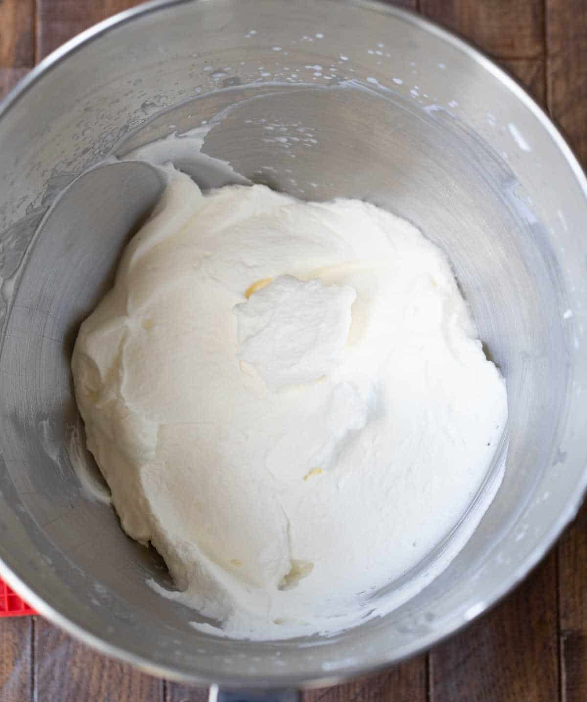Whipped cream in a silver mixing bowl. 