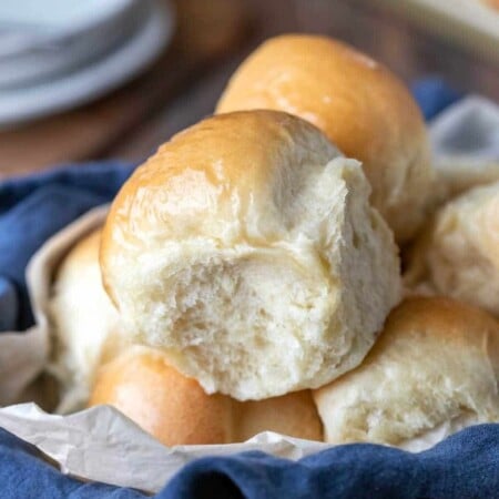 Dinner rolls in a blue linen napkin lined basket.