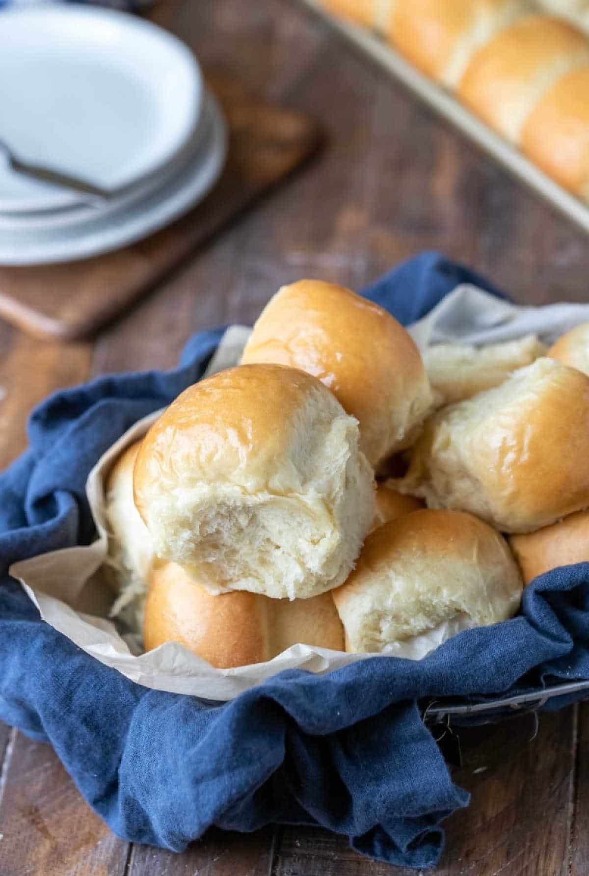 A tray of dinner rolls next to a bread basket. 