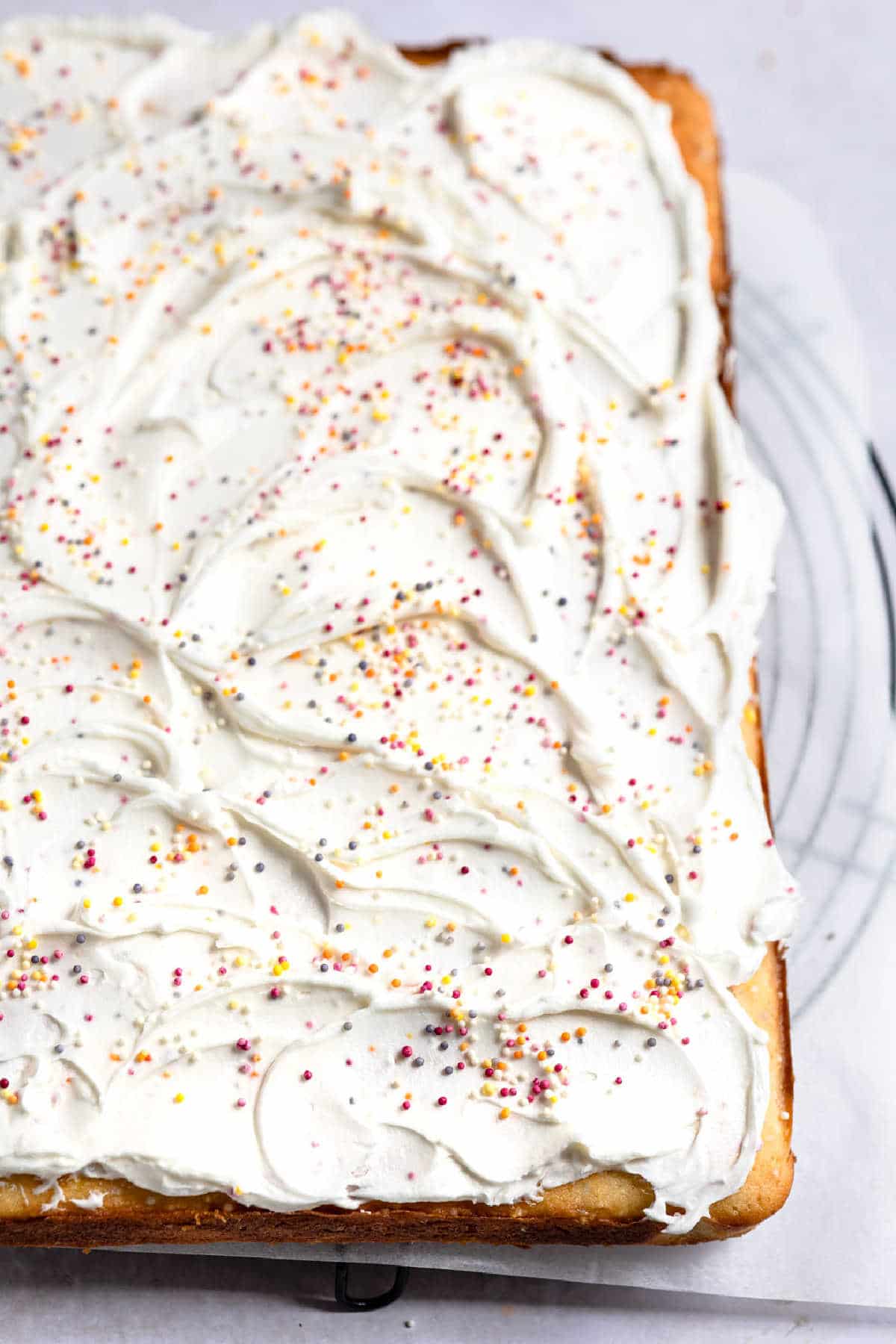 A frosted funfetti cake topped with sprinkles. 
