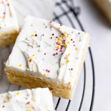 A slice of funfetti cake frosted with vanilla frosting and sprinkles.