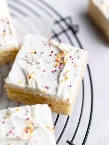 A slice of funfetti cake frosted with vanilla frosting and sprinkles.