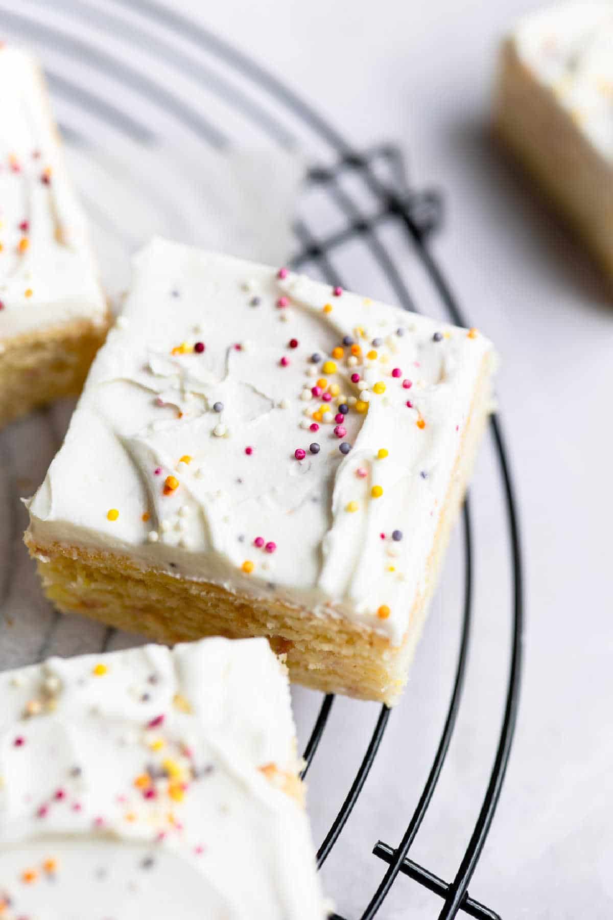 A slice of funfetti cake frosted with vanilla frosting and sprinkles. 