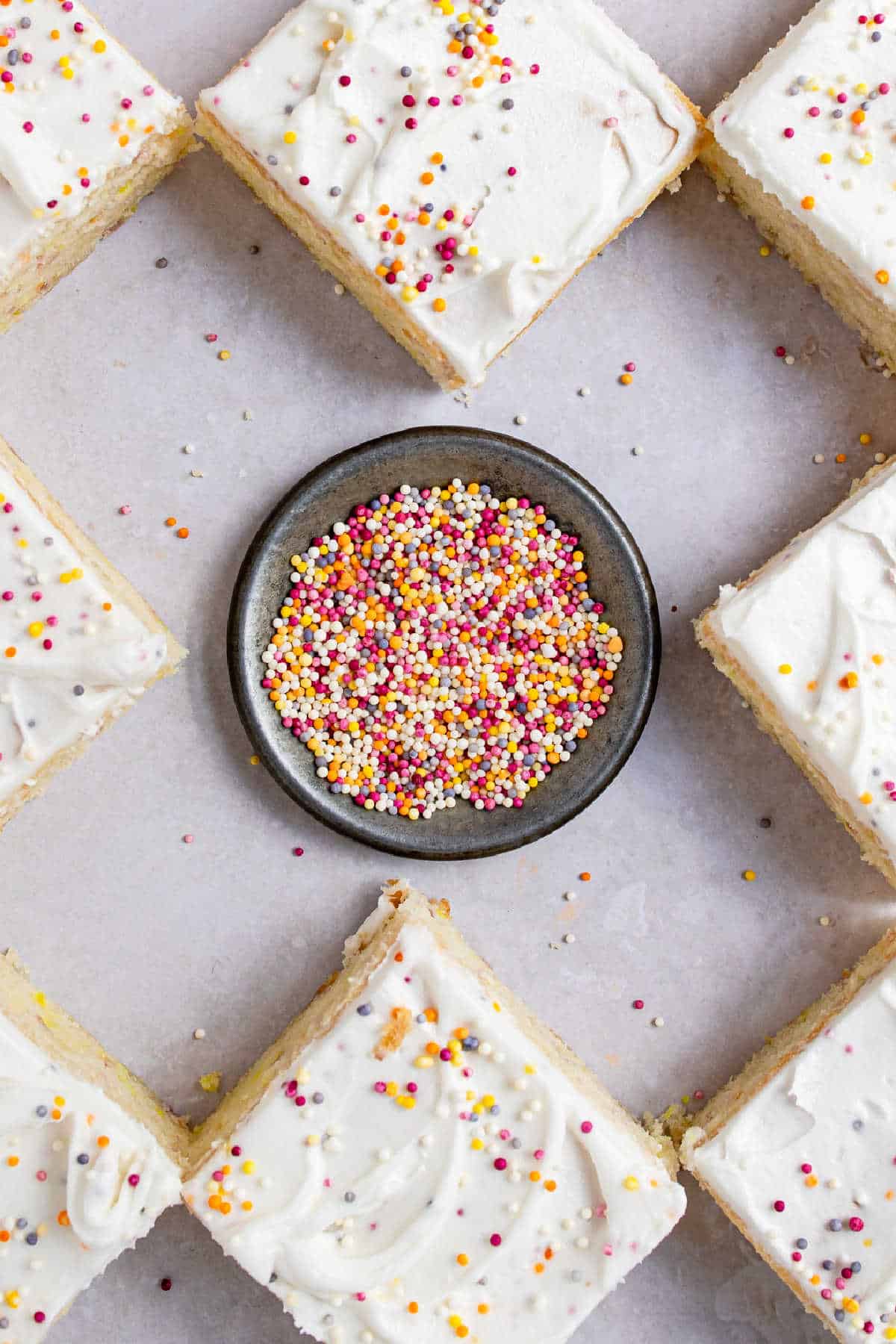 A dish of sprinkles in the middle of slices of cake. 