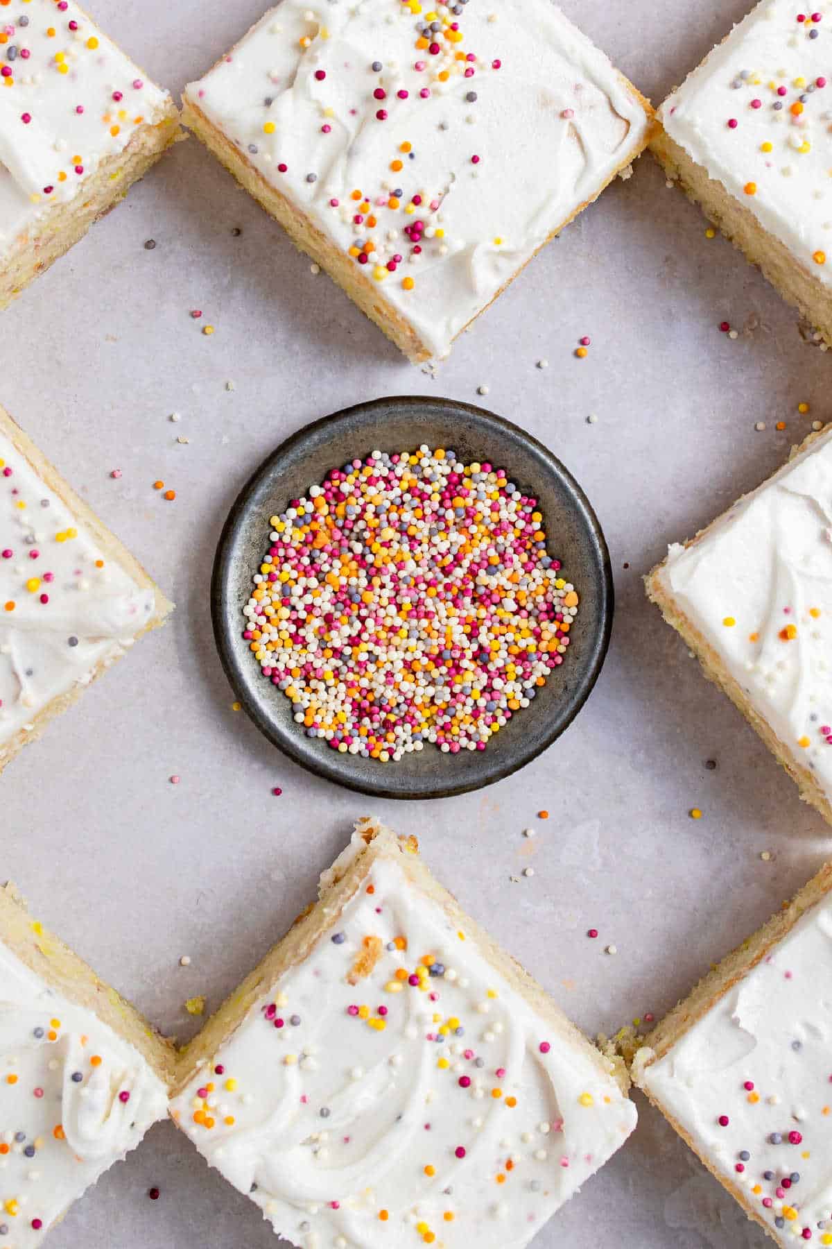 A dish of sprinkles in the middle of slices of cake.