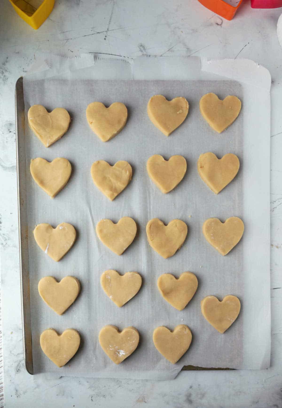 unbaked heart shaped sugar cookies on a baking sheet. 