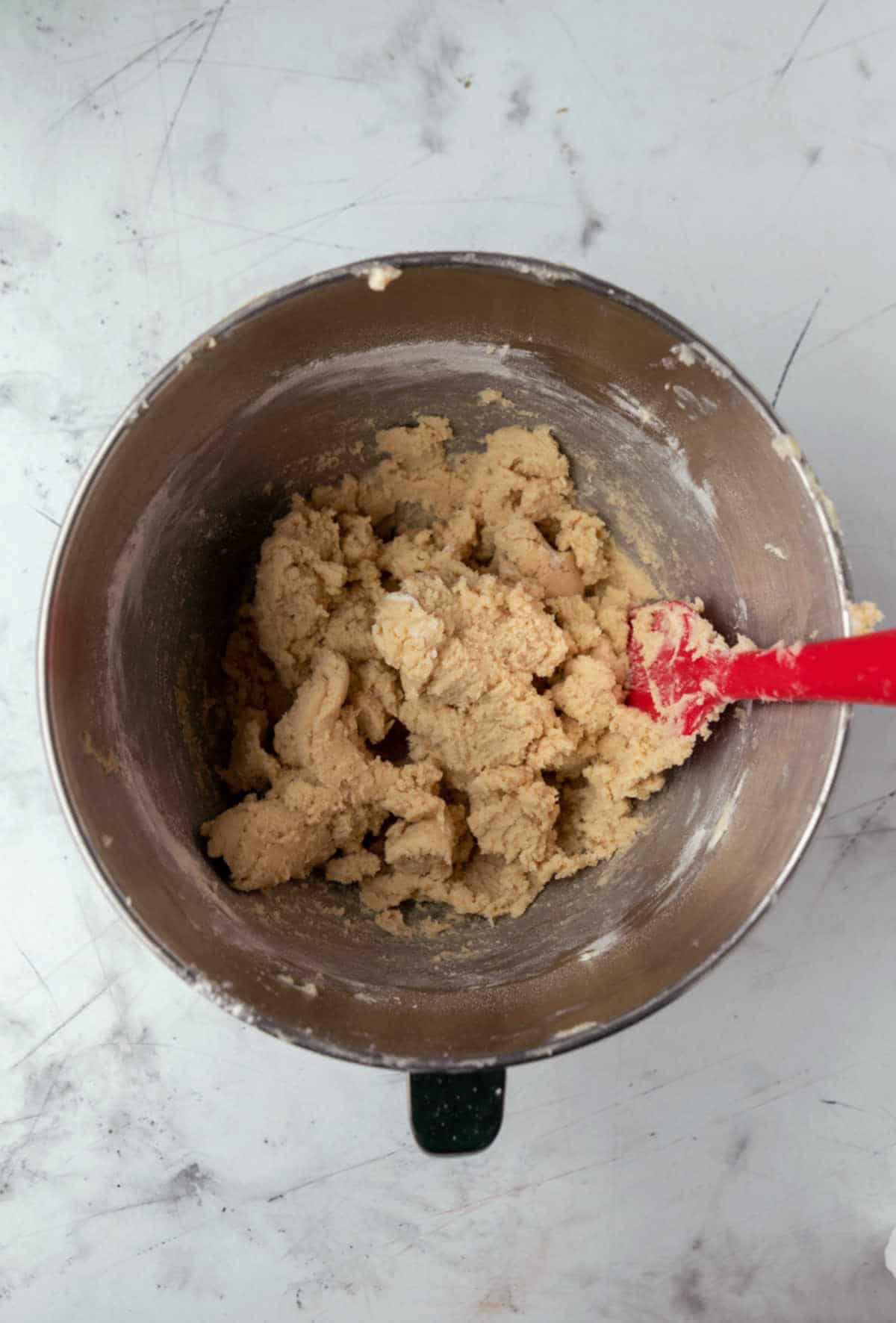 Sugar cookie dough in a silver mixing bowl.