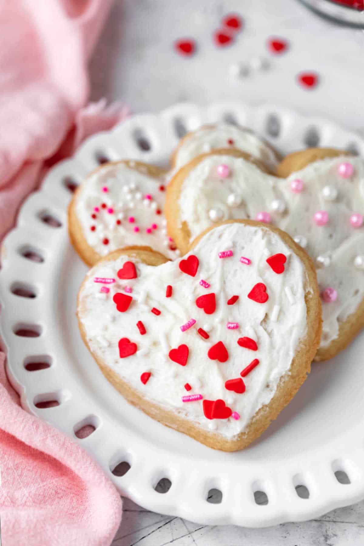 Three heart shaped sugar cookies on a white plate.