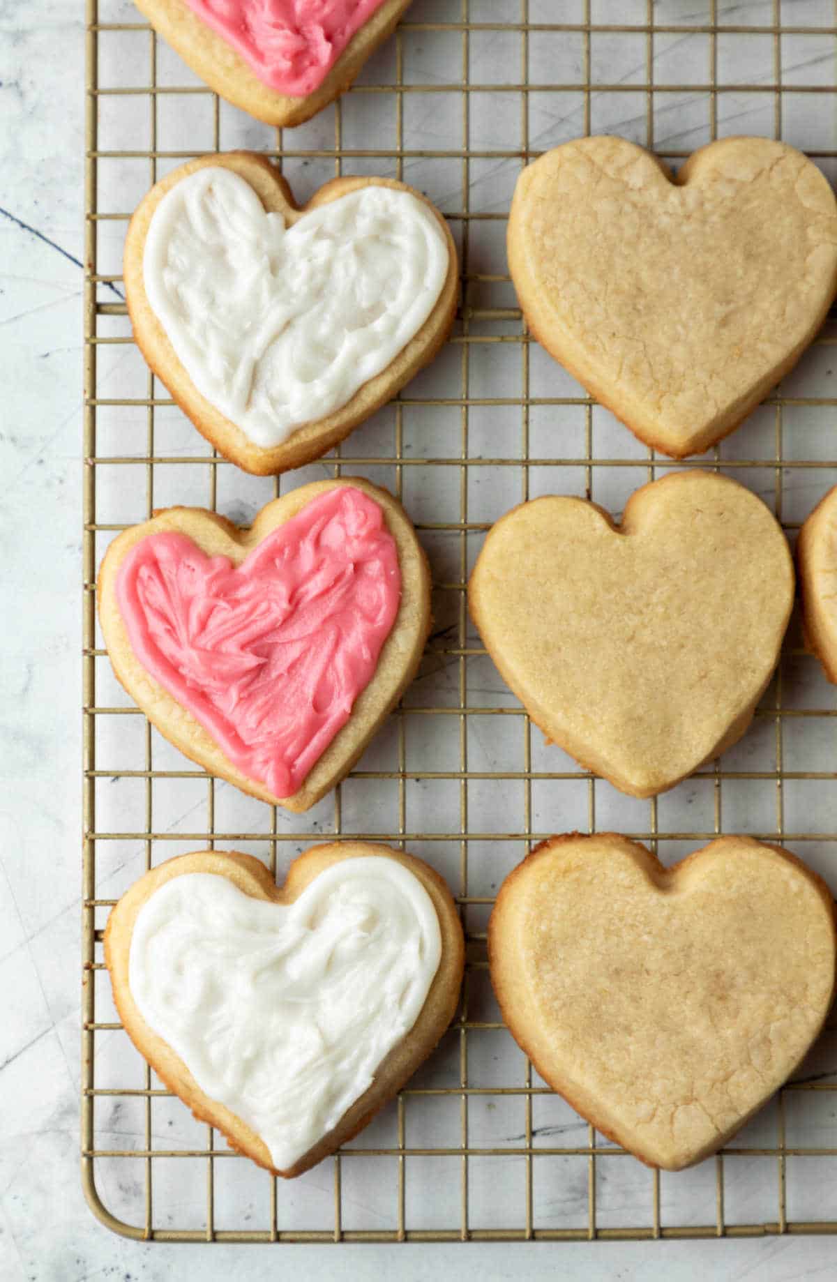 One row of frosted sugar cookies on a wire cooling rack. 