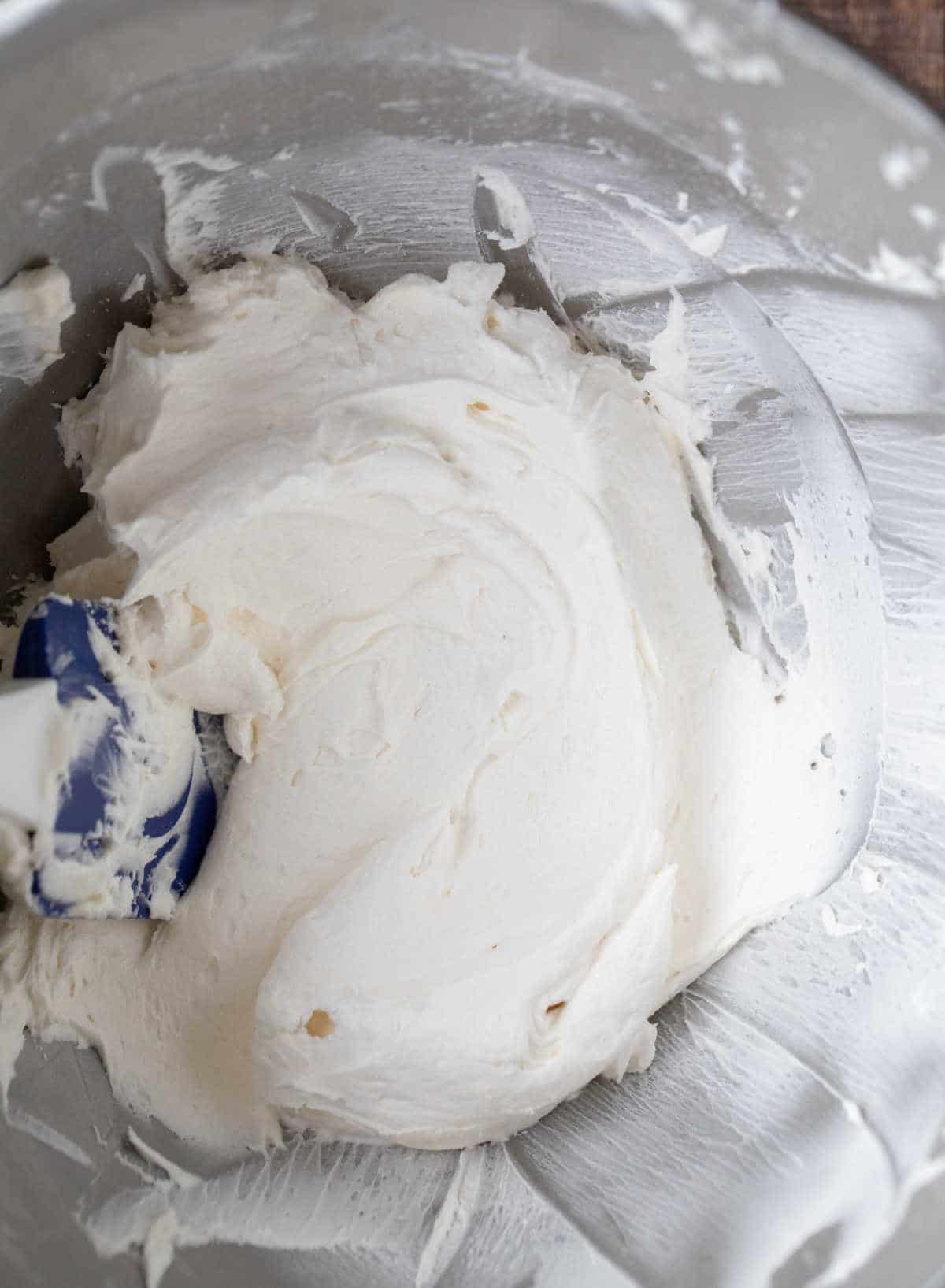 Vanilla buttercream frosting in a silver mixing bowl.