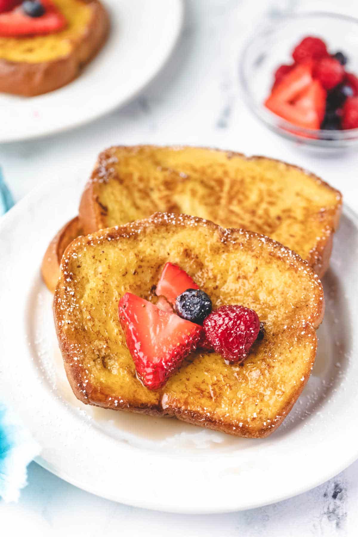 Stack of brioche French toast with berries on it.