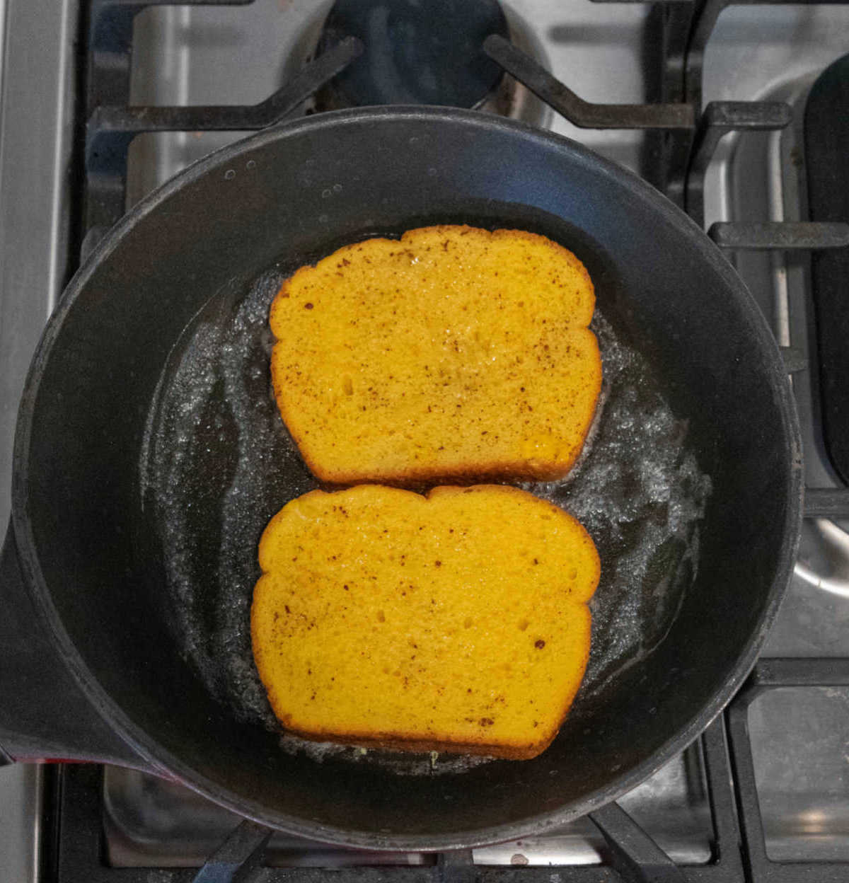 Two pieces of brioche French toast in a skillet.