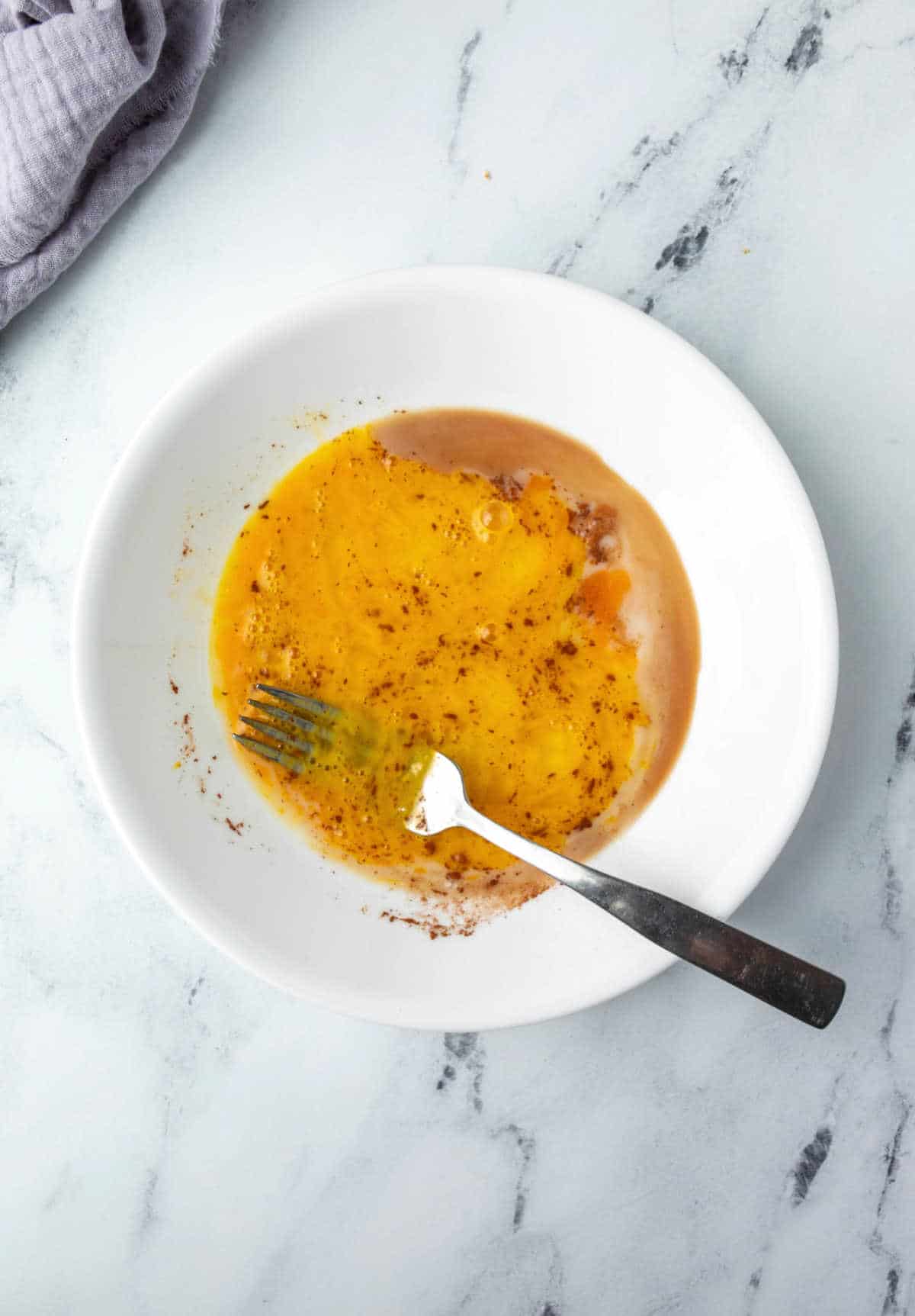 French toast egg mixture in a white dish.