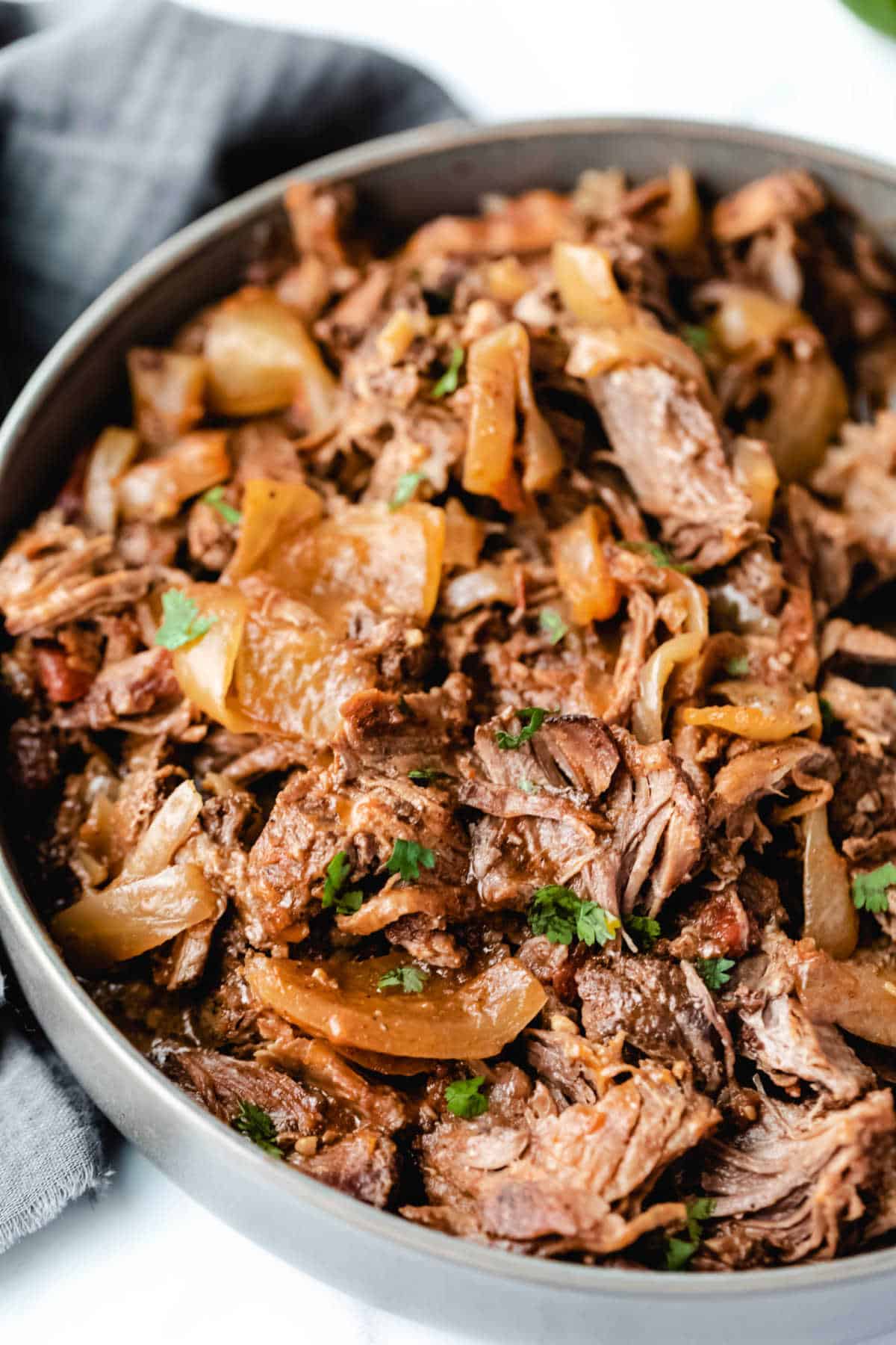 Gray bowl filled with Mexican shredded beef and onions. 