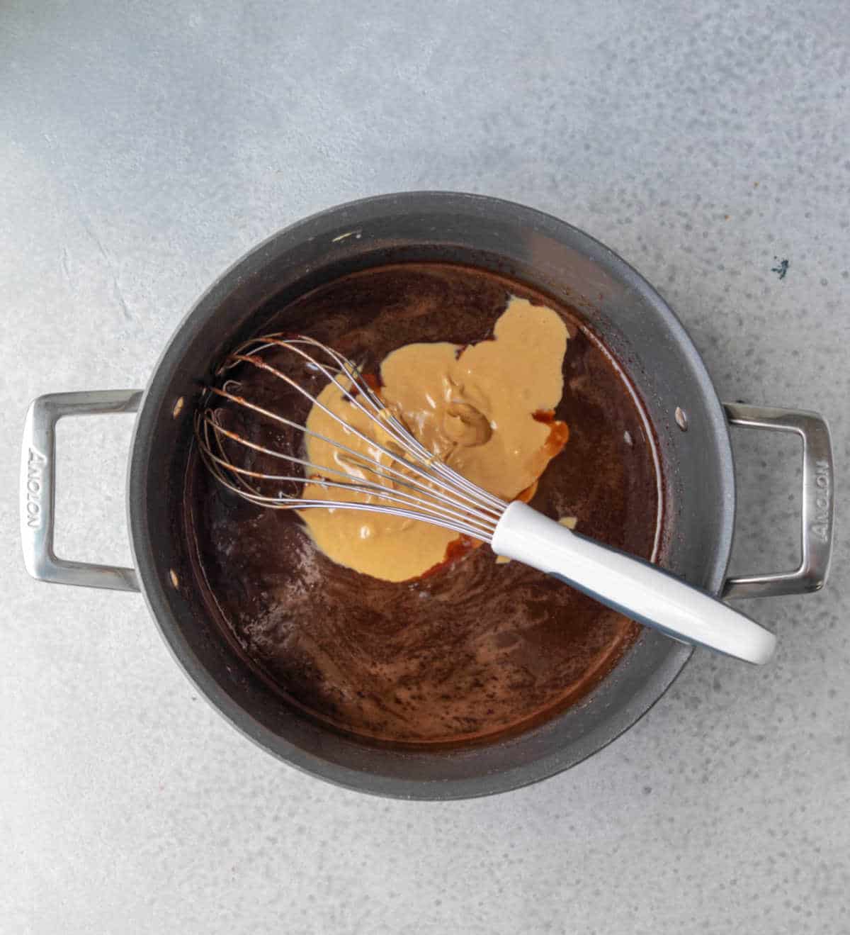 Peanut butter and vanilla on top of chocolate mixture in a saucepan.