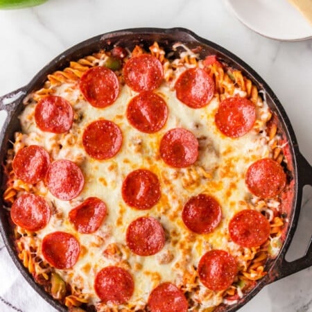 Pizza pasta in a pan next to a wooden spoon.