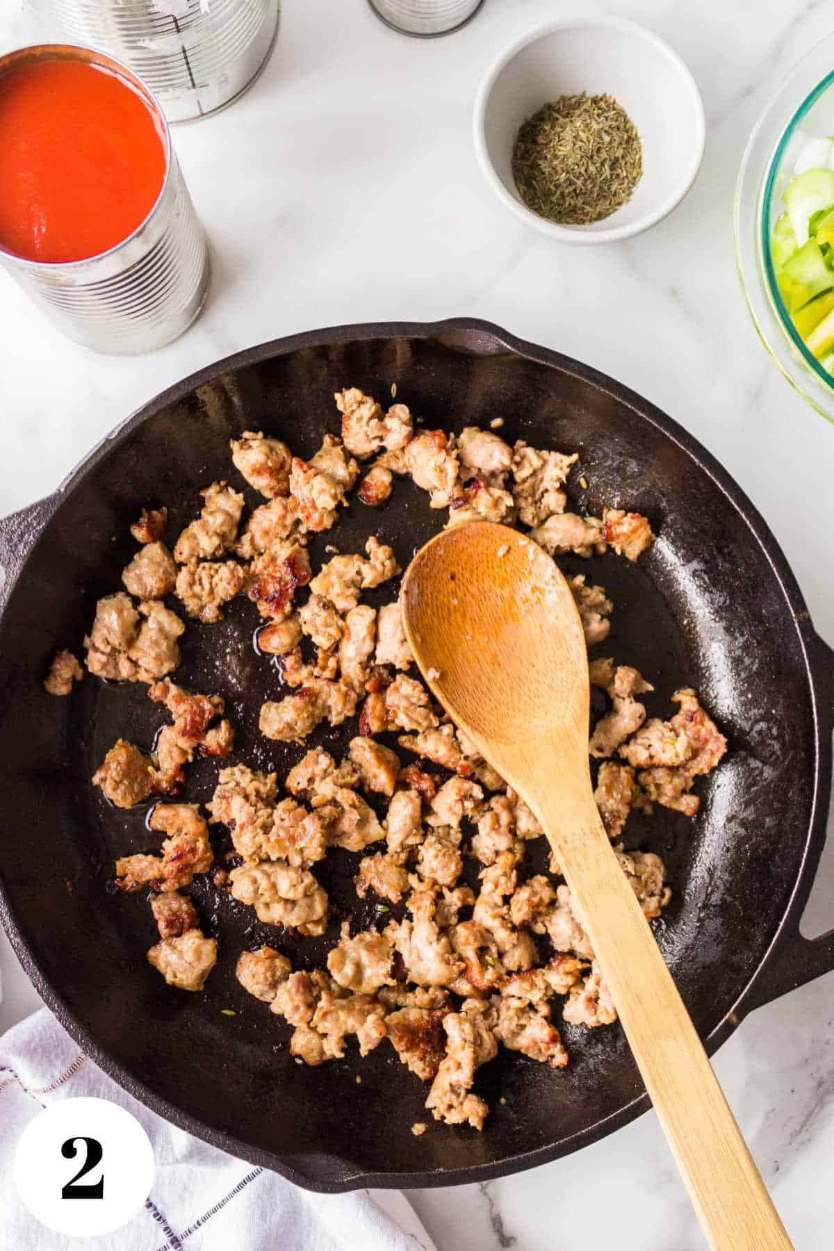 Browned Italian sausage in a skillet.