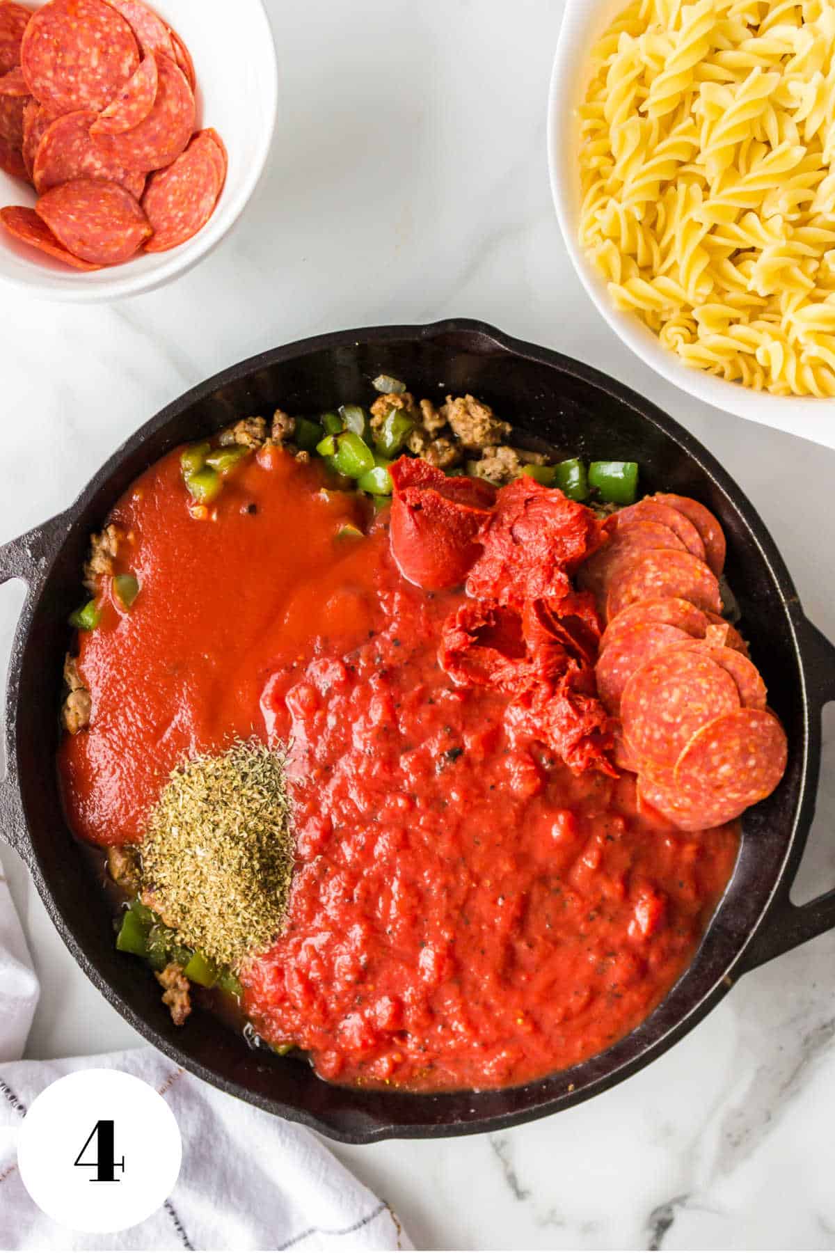 Tomato sauce crushed tomatoes and pepperoni in a skillet.