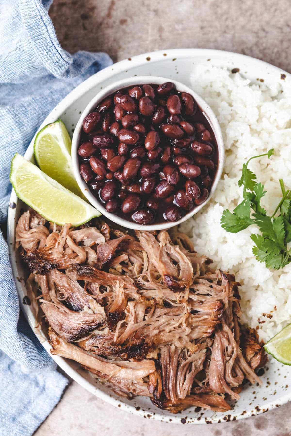 A speckled dish with cuban mojo pork and lime slices. 