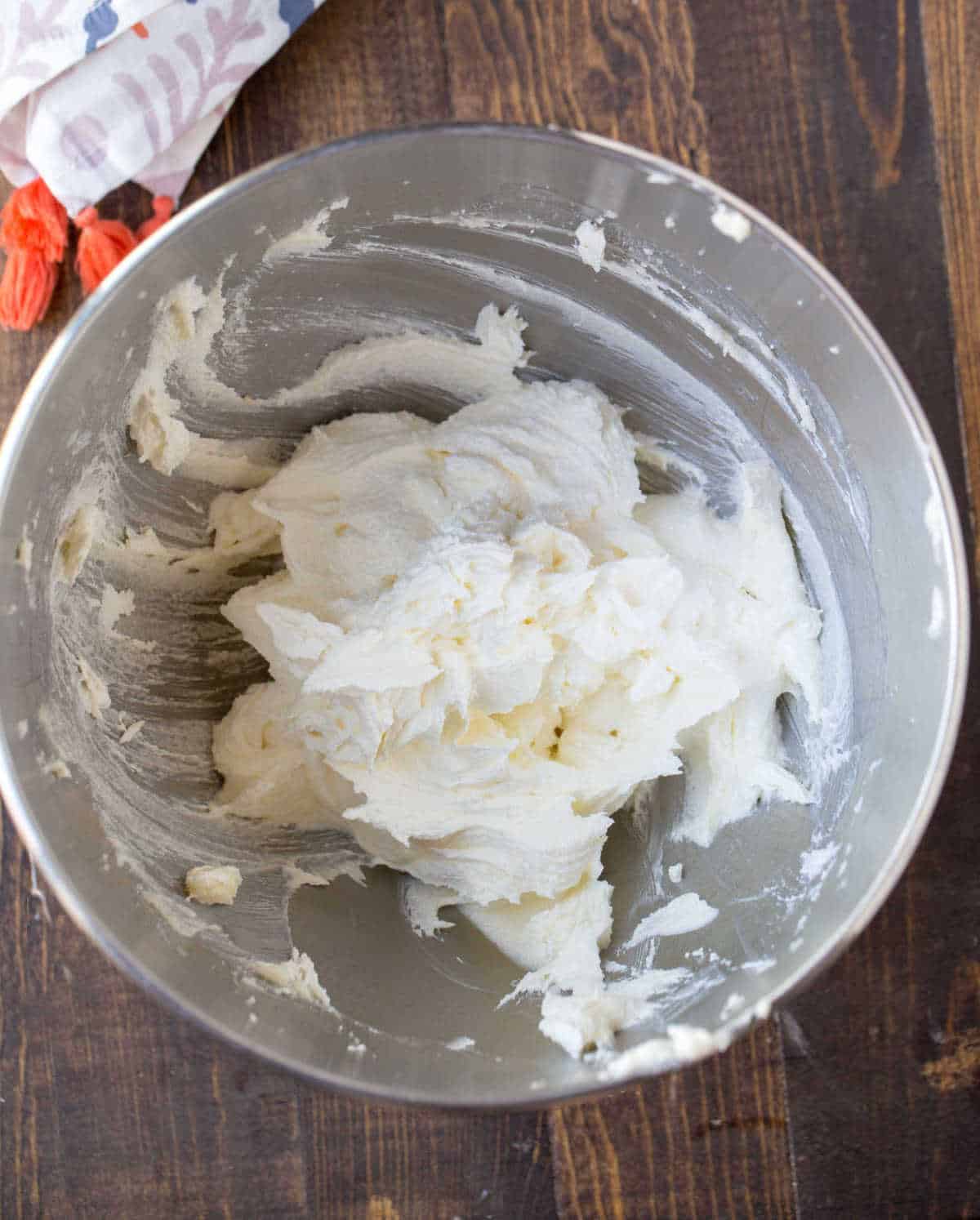 Whipped buttercream frosting in a silver mixing bowl. 