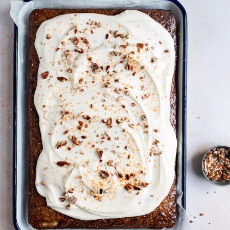 Frosted carrot sheet cake on a baking tray.