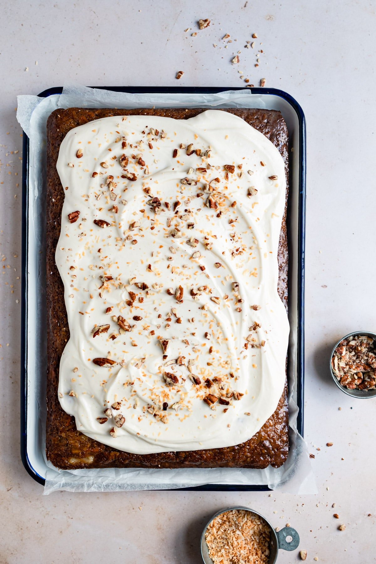 Frosted carrot sheet cake on a baking tray.