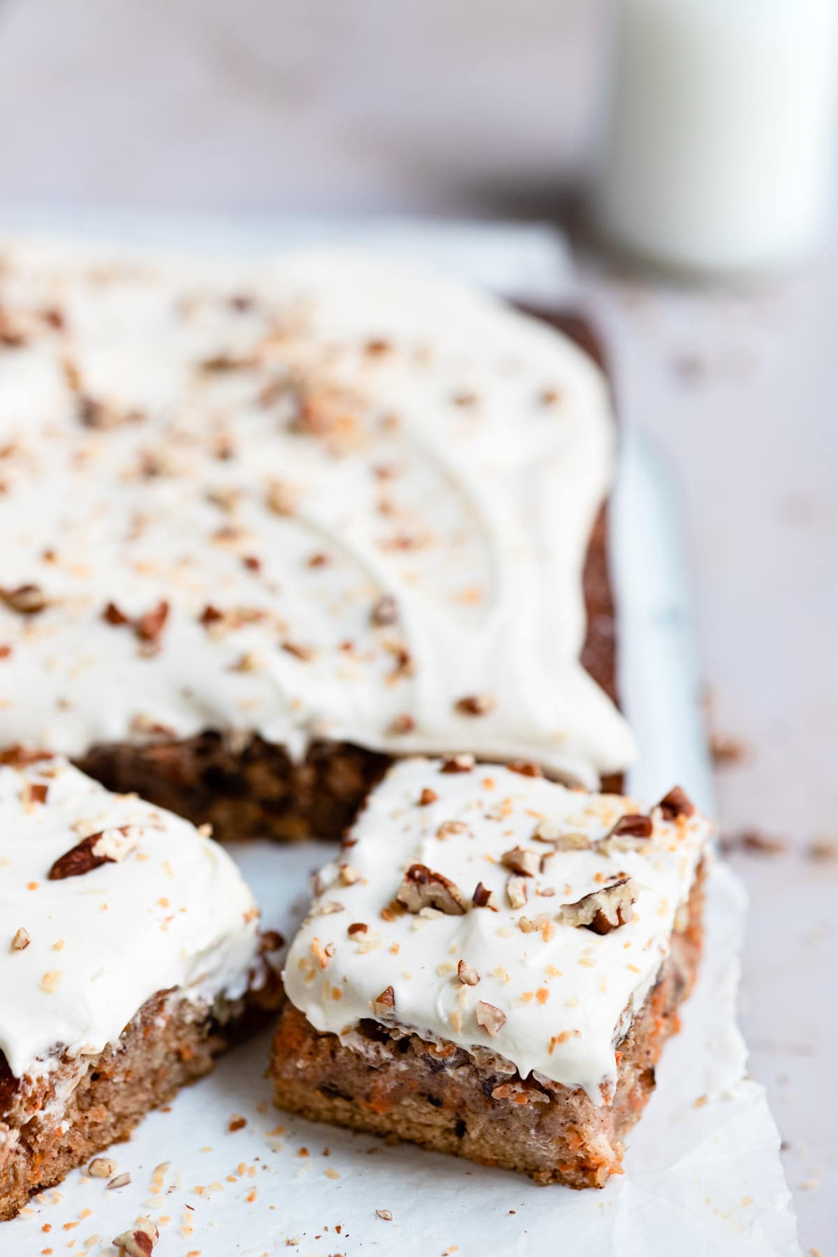 A piece of carrot cake cut from a sheet cake.