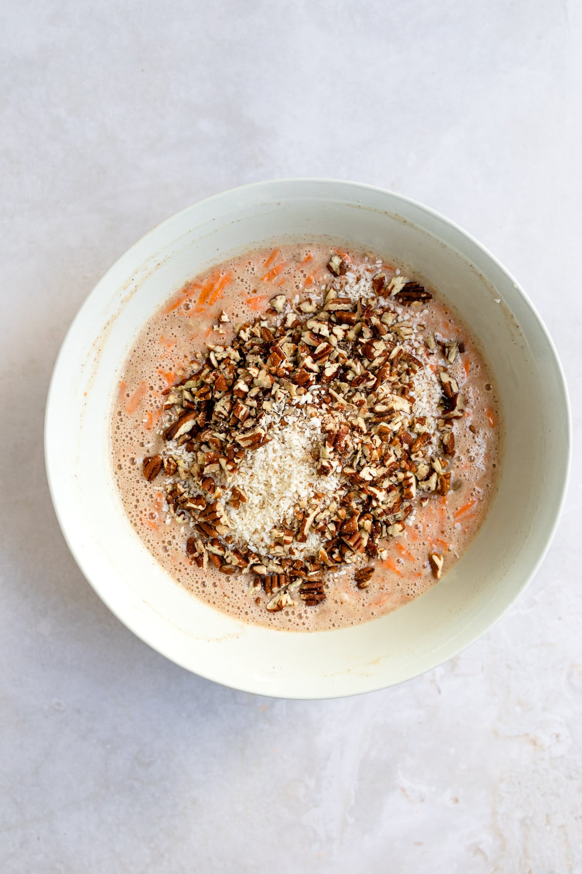 Carrot cake batter topped with nuts and coconut.