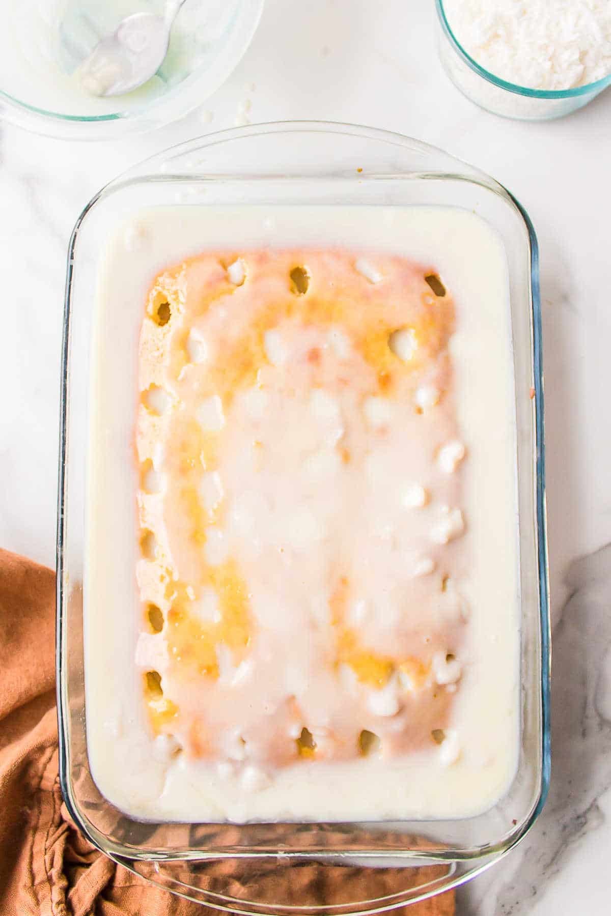 Coconut filling poured on top of coconut cake. 