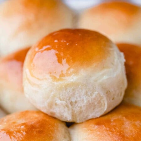 A Hawaiian roll sitting on top of a stack of rolls.