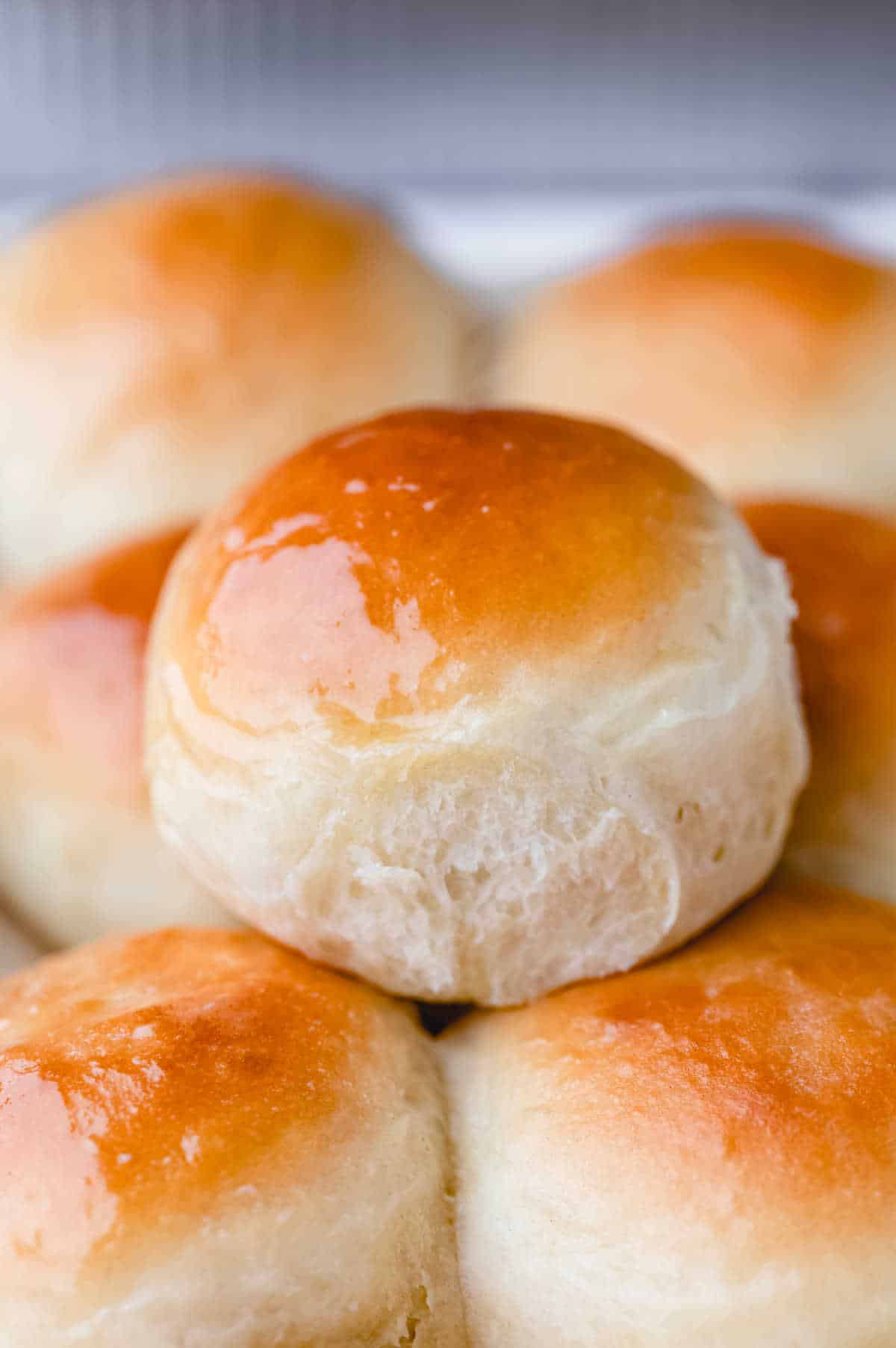 A Hawaiian roll sitting on top of a stack of rolls. 