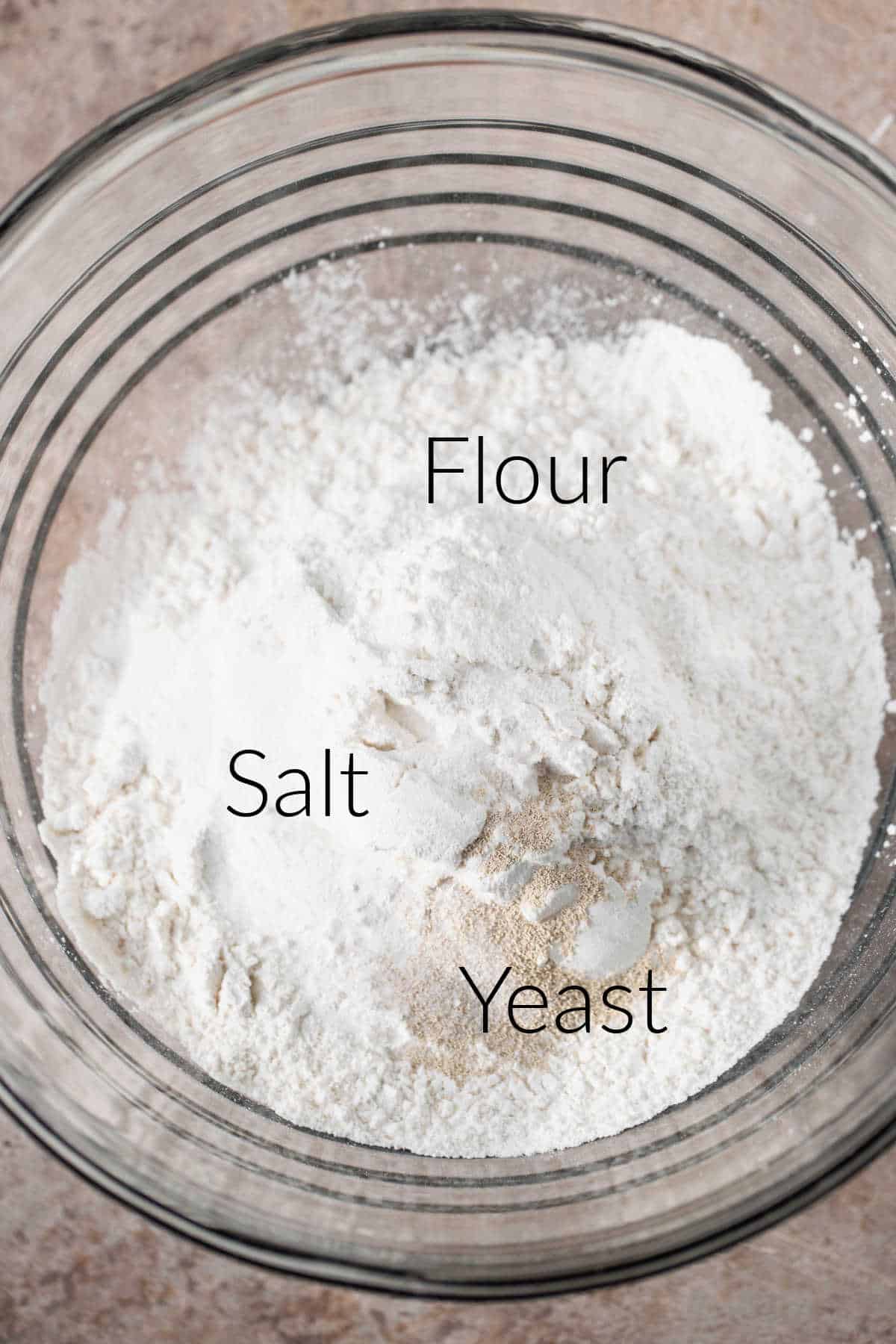 Ingredients for no knead bread in a glass mixing bowl. 