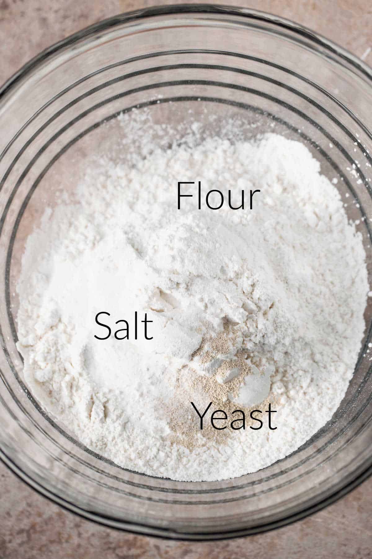 Ingredients for no knead bread in a glass mixing bowl.