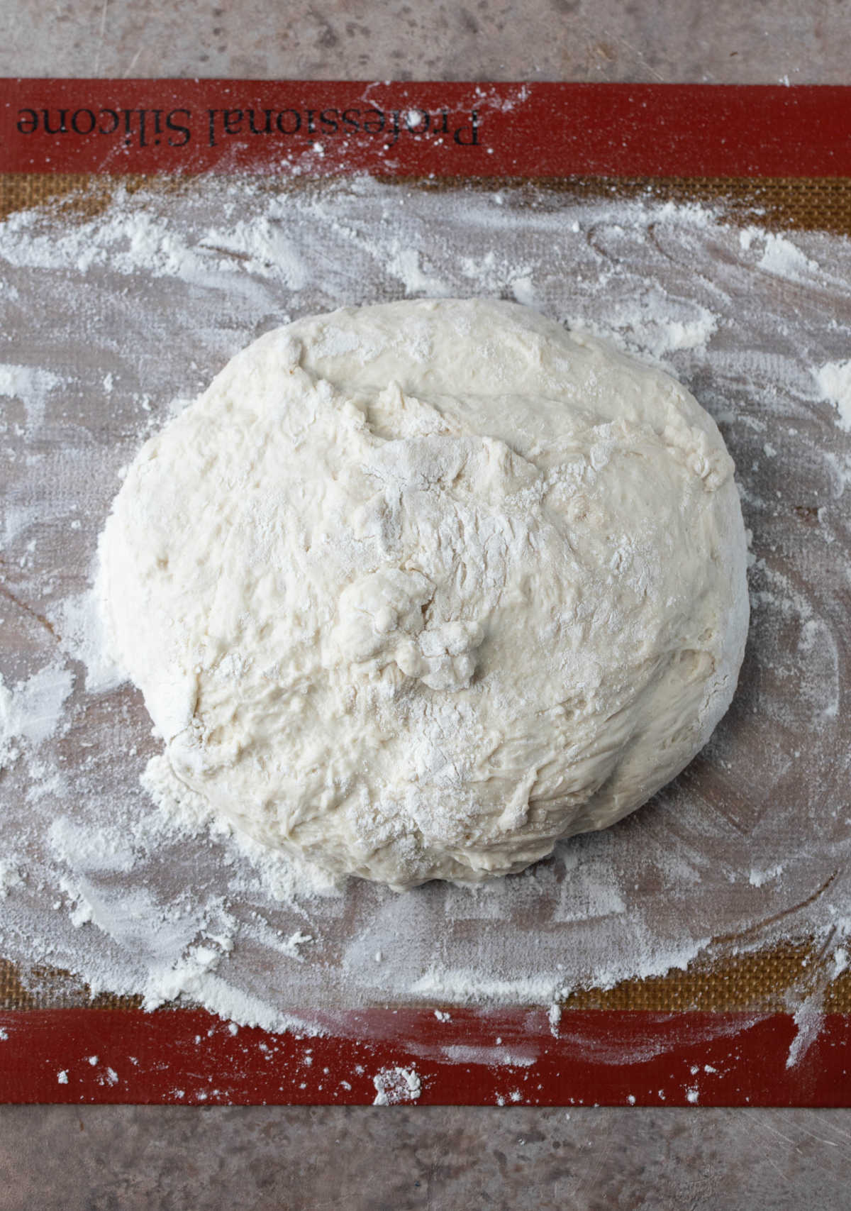 No knead bread dough in a ball on a floured surface. 