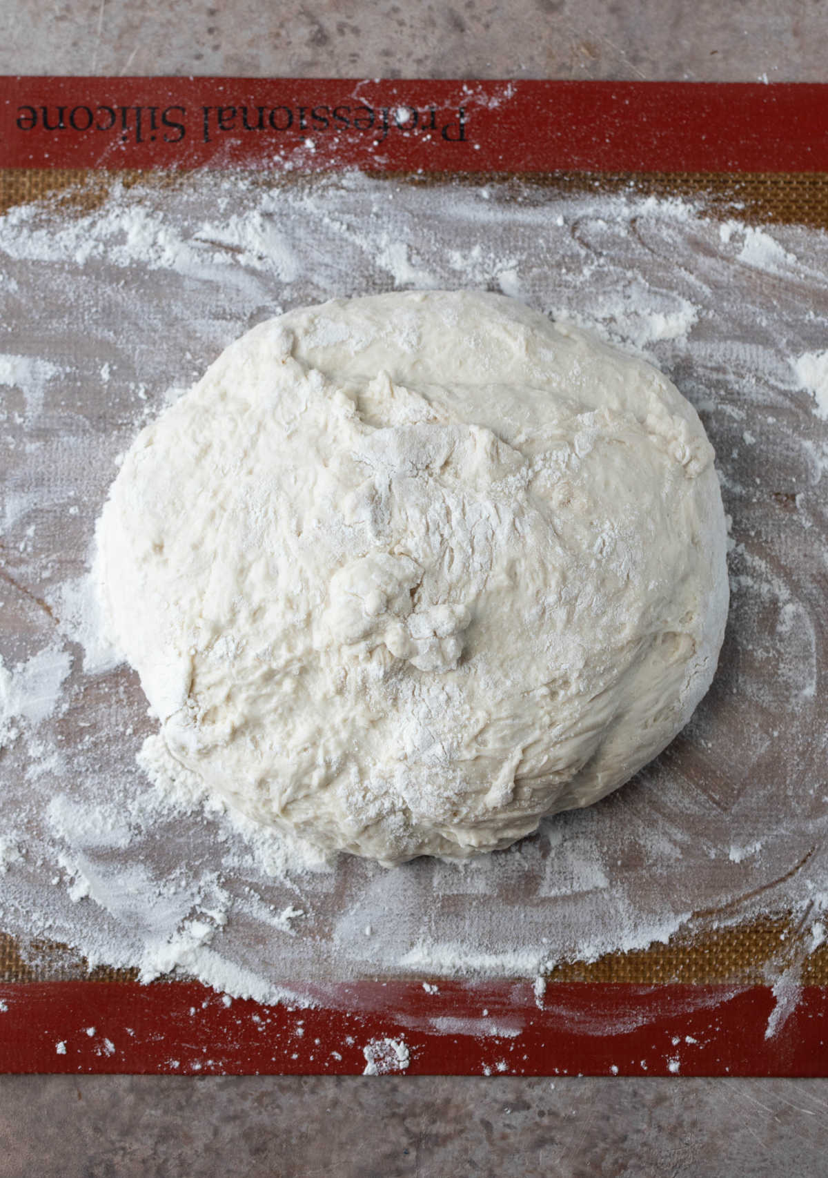 No knead bread dough in a ball on a floured surface.