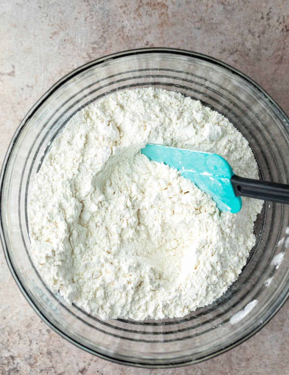 Dry ingredients for no knead bread in a glass mixing bowl.