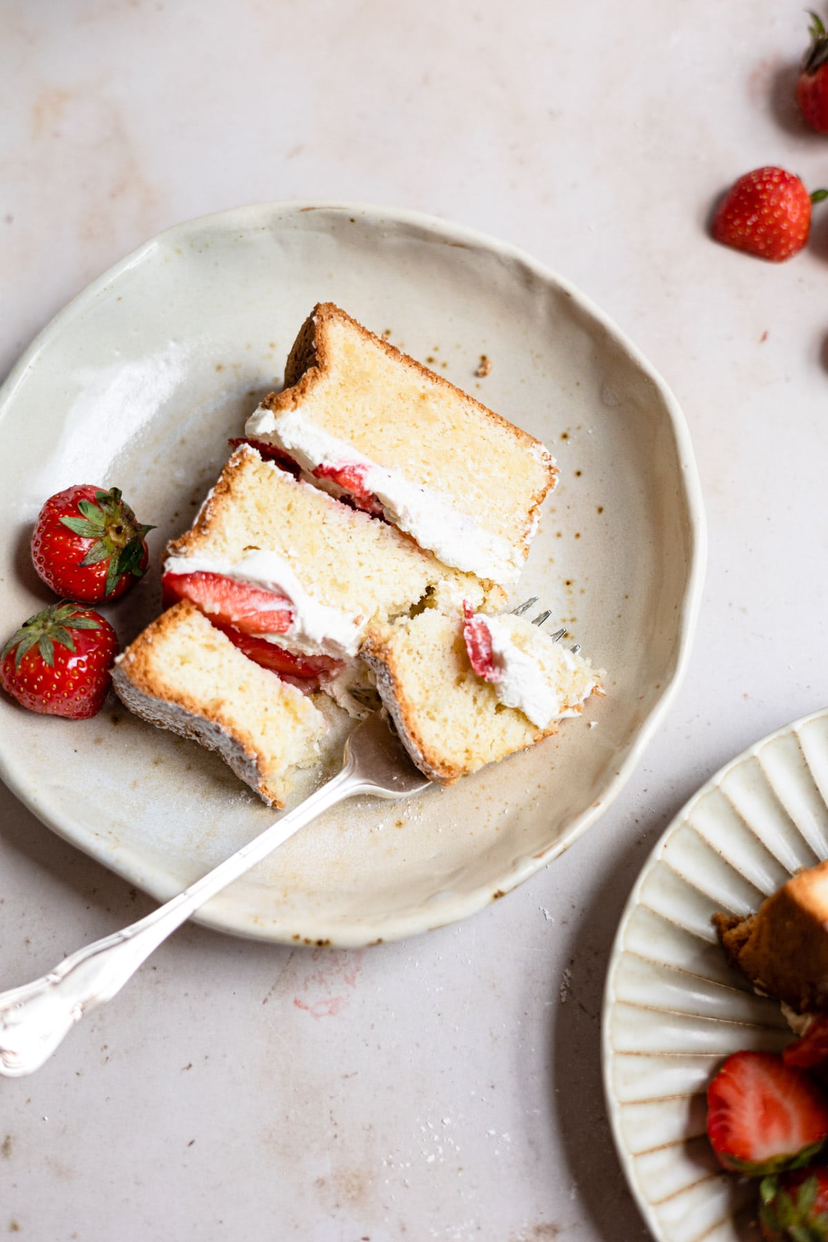 A fork taking a bite of strawberry shortcake cake. 