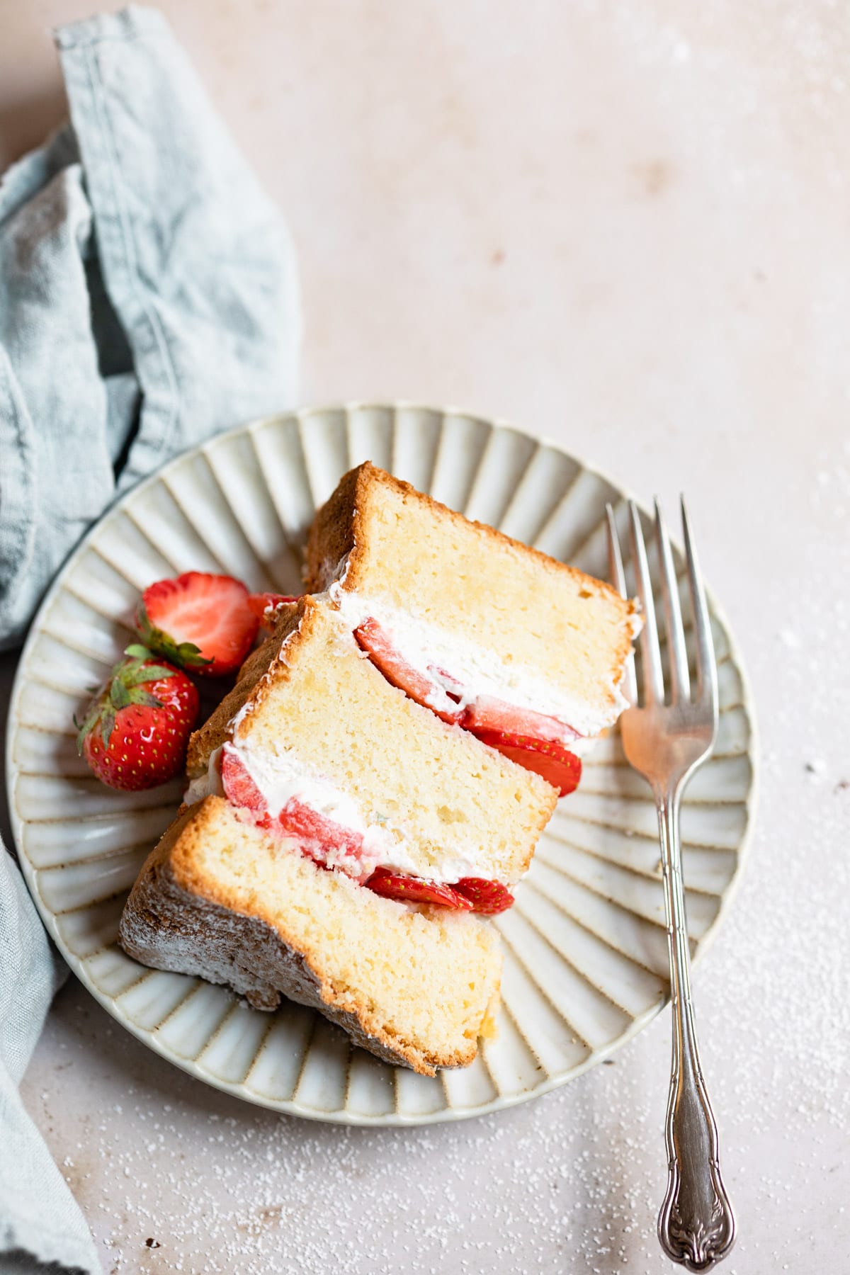 A piece of strawberry shortcake cake on a plate with strawberries and a fork. 