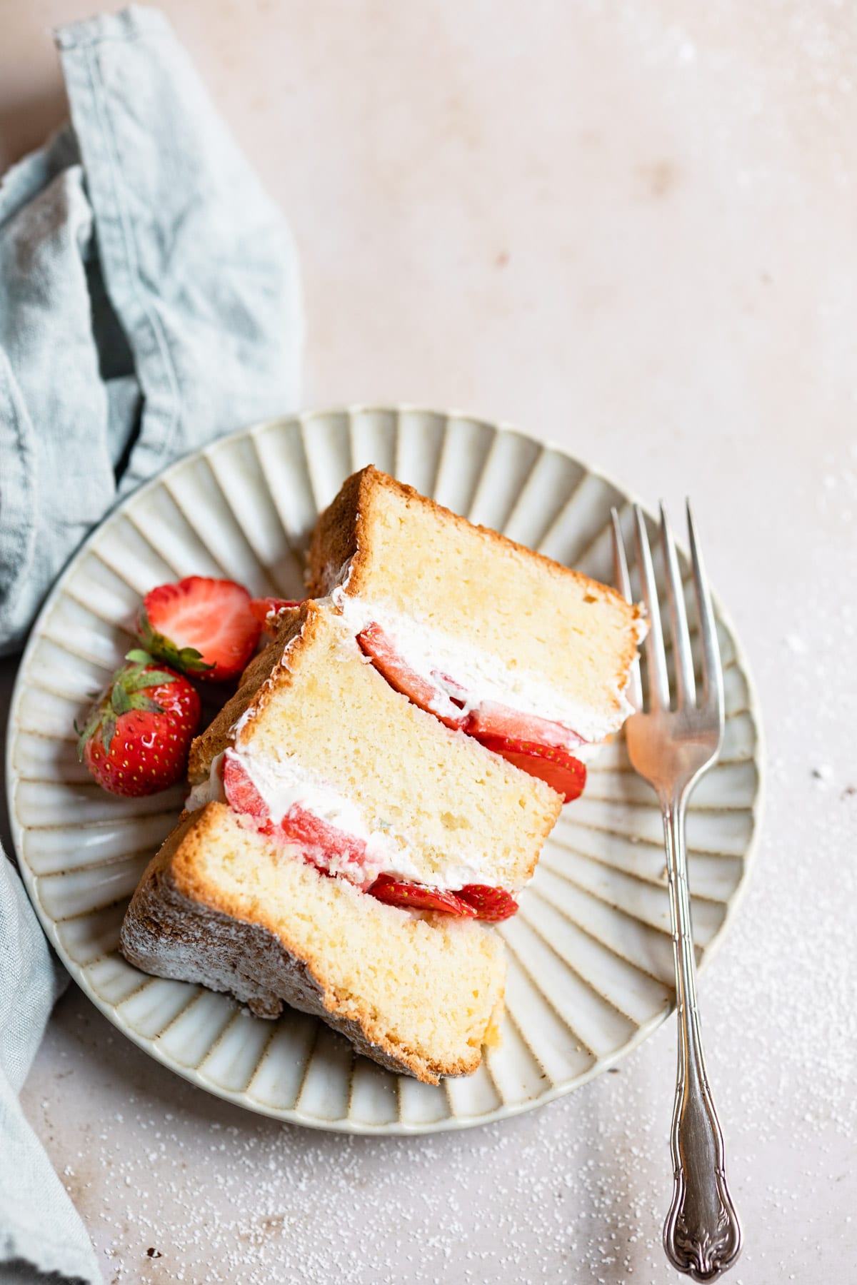 A piece of strawberry shortcake cake on a plate with strawberries and a fork.